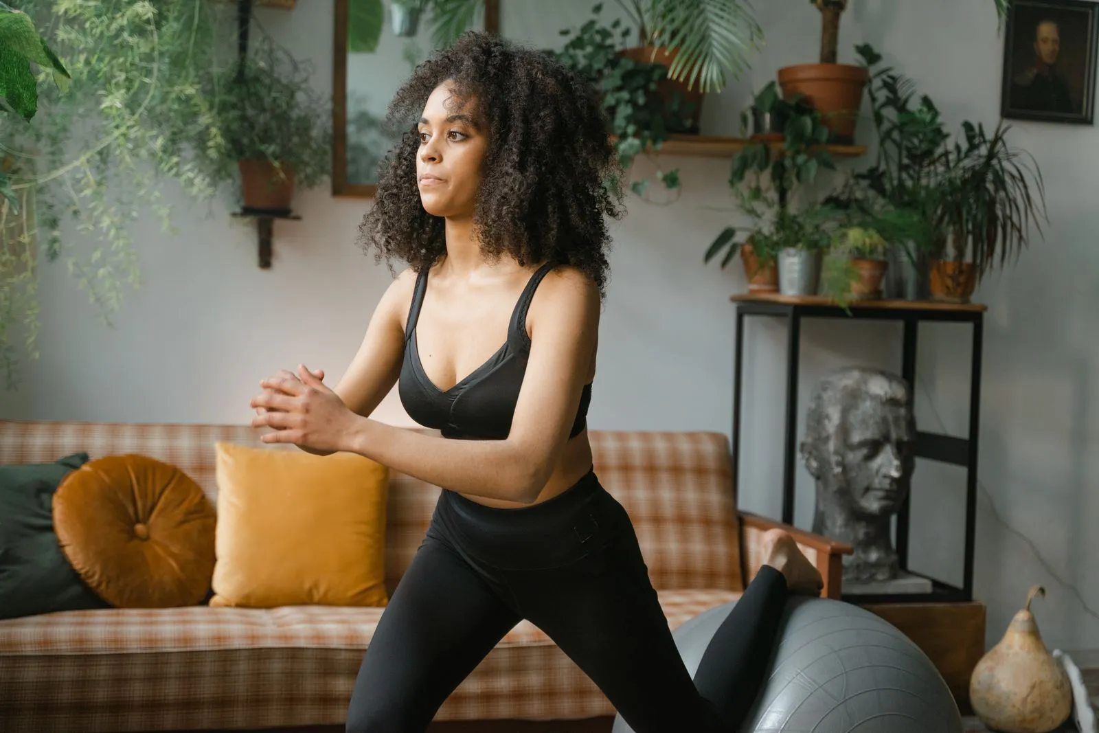 A woman mid-stretch in a plant-filled living room