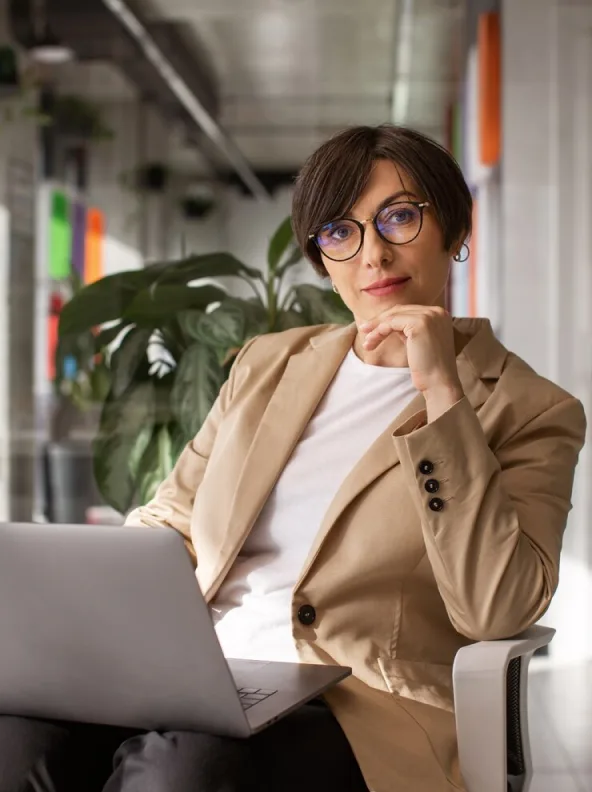 A woman in glasses working from an armchair in a studio office
