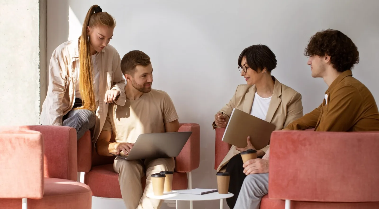 A team of four talking in armchairs around a coffee table