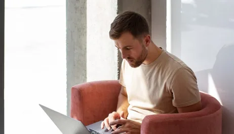 A man working from a red armchair