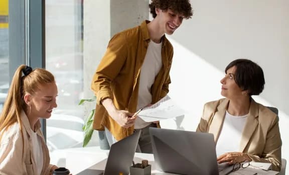 Three colleagues reviewing printed pages together at a desk